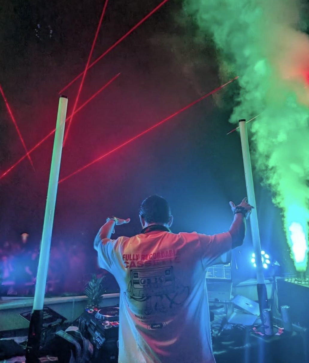 DJ performing with lasers and fog at a festival-style event