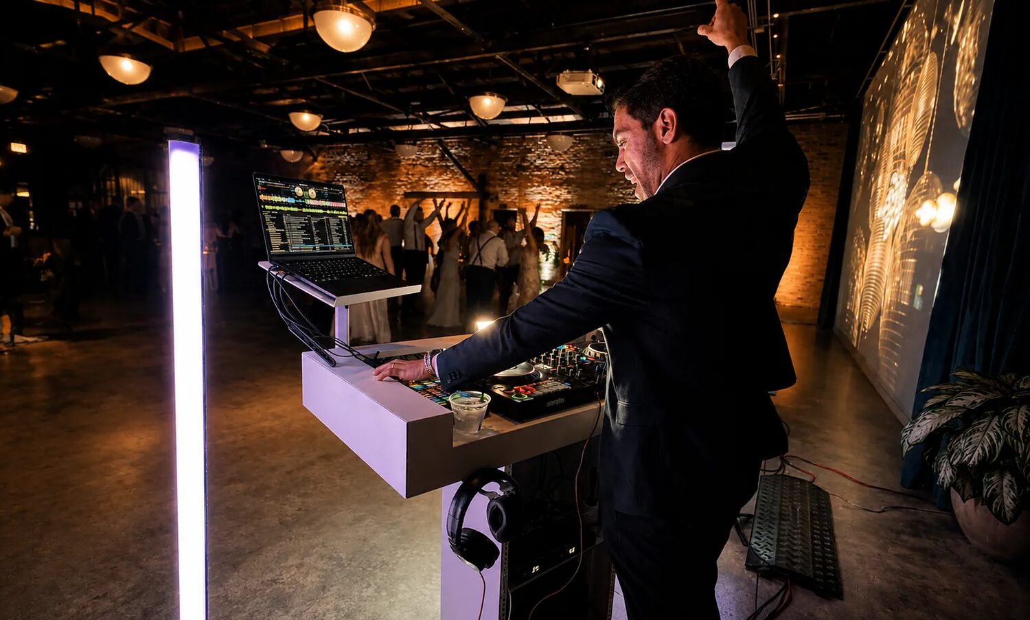DJ Fidel with arms raised as the dance floor erupts