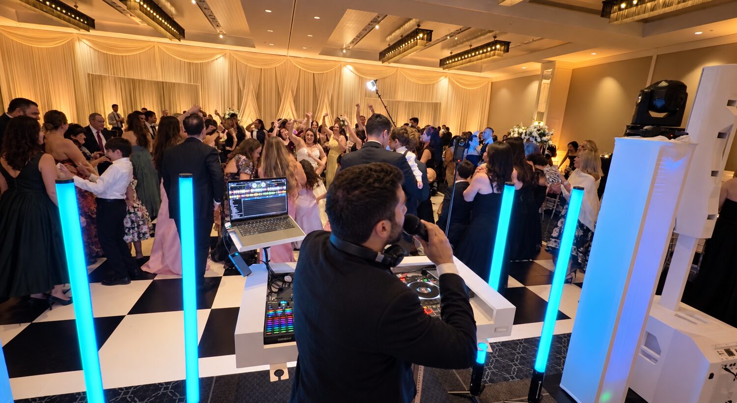 Packed wedding dance floor under color-changing light towers