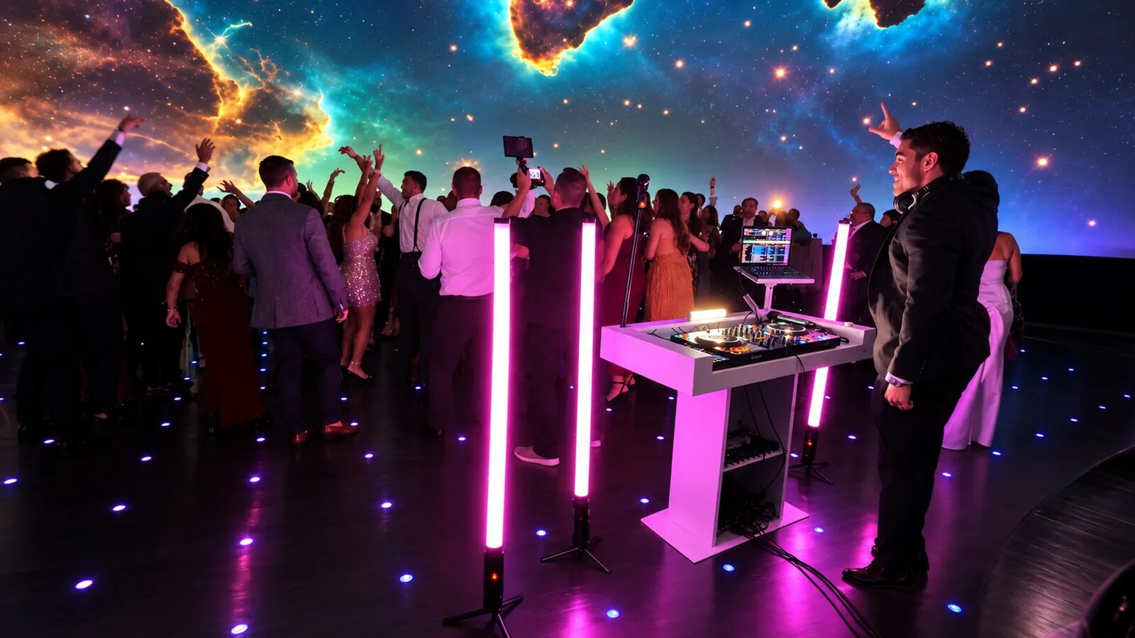 A packed dance floor under a giant galaxy projection at a DJ Fidel event