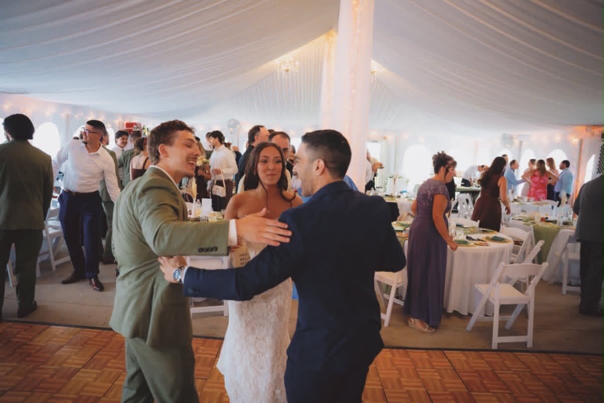 Jersey and Nathan embracing a guest inside the tented reception at Northfork Farm