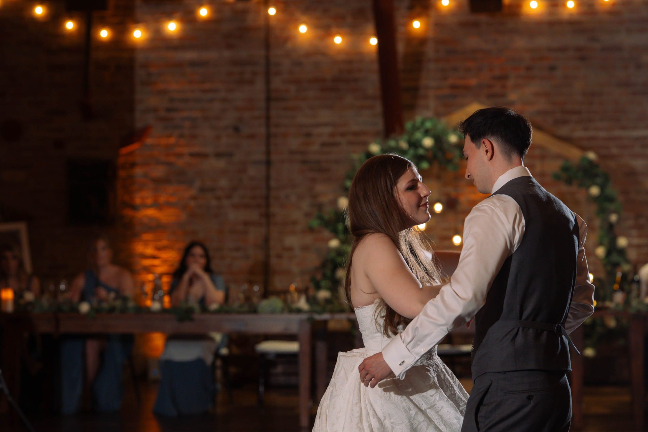 Bride and groom during their first dance under string lights